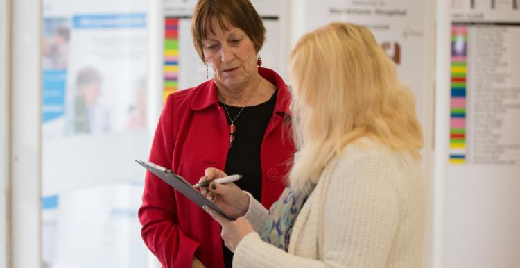 woman with clipboard talking to another woman