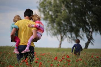 father carrying kids through field of poppies