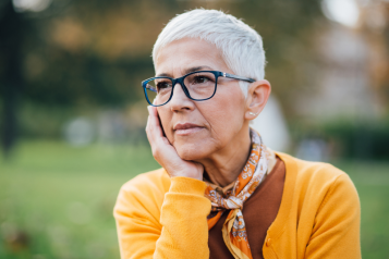 older woman with short cropped hair and glasses and wearing a yellow cardigan