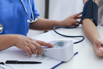 A doctor checking a woman's blood pressure.