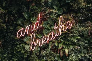 neon sign saying and breathe
