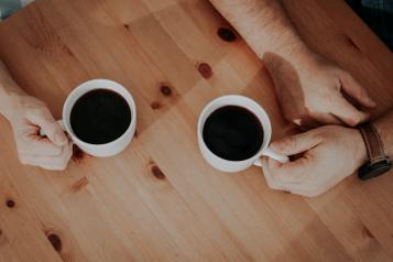 two people with their hands around coffee mugs