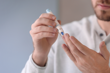 man using finger prick blood sugar test kit