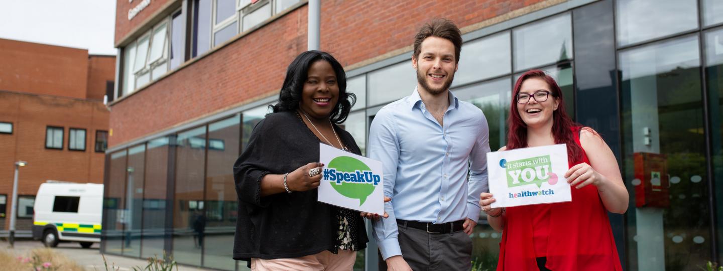 Group of Healthwatch volunteers outside a hospital holding 'Speak up' sign